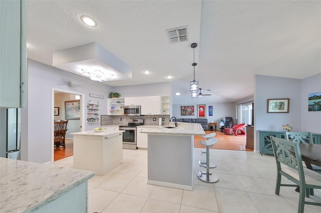 kitchen with stainless steel appliances, sink, white cabinetry, a kitchen island, and hanging light fixtures