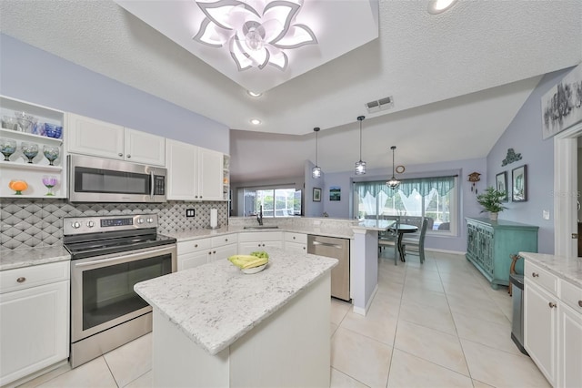 kitchen featuring lofted ceiling, white cabinetry, a kitchen island, kitchen peninsula, and stainless steel appliances