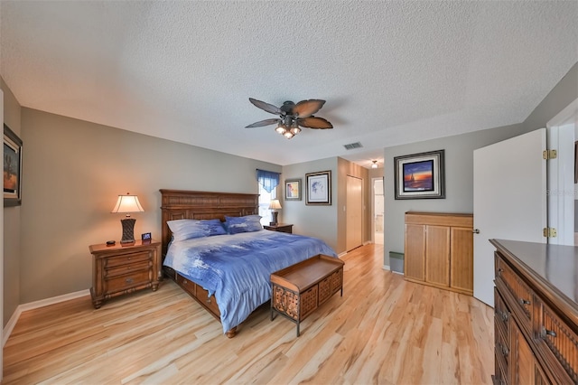 bedroom with a textured ceiling, light wood-type flooring, and ceiling fan