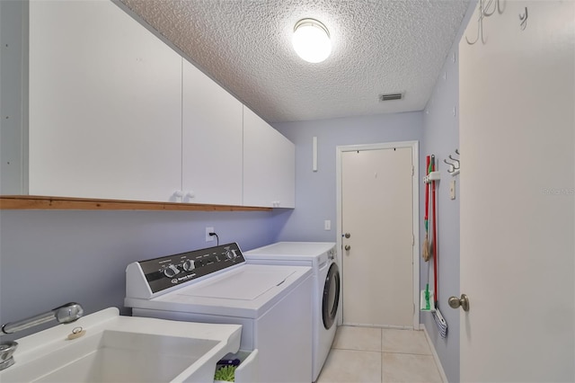 laundry room featuring cabinets, a textured ceiling, sink, light tile patterned floors, and independent washer and dryer