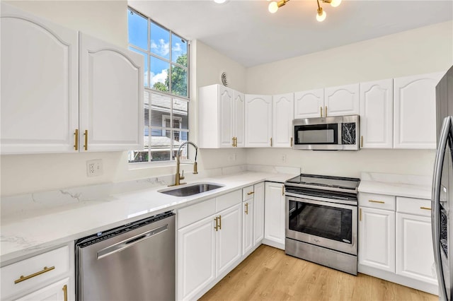 kitchen featuring white cabinetry, stainless steel appliances, sink, and light hardwood / wood-style flooring