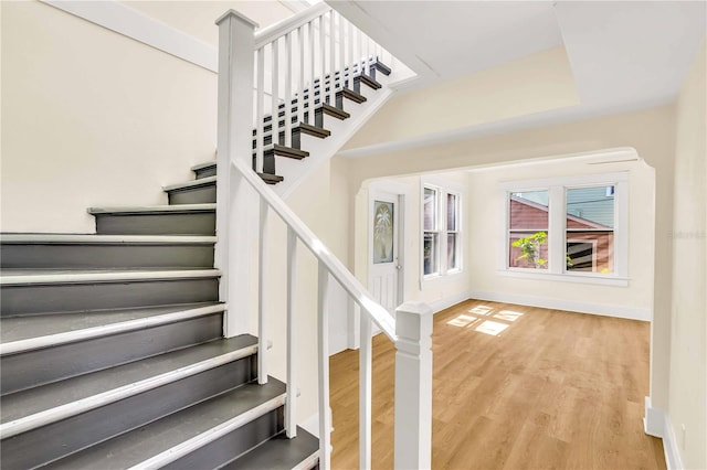 staircase with a tray ceiling and light wood-type flooring