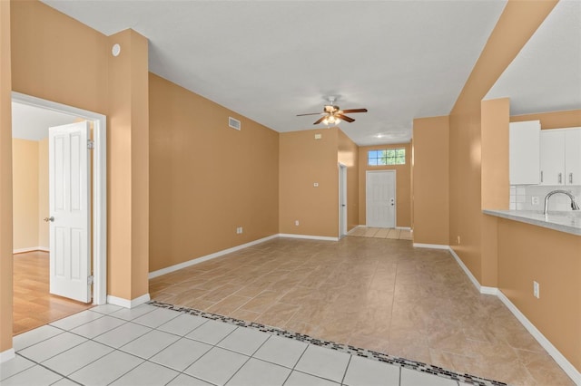 unfurnished living room with ceiling fan and sink