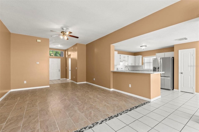 interior space featuring white cabinetry, sink, ceiling fan, stainless steel refrigerator with ice dispenser, and kitchen peninsula