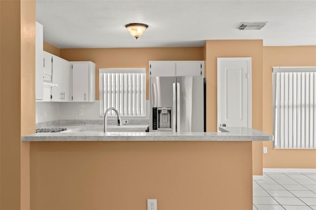 kitchen with white cabinetry, stainless steel fridge with ice dispenser, kitchen peninsula, extractor fan, and light tile patterned floors