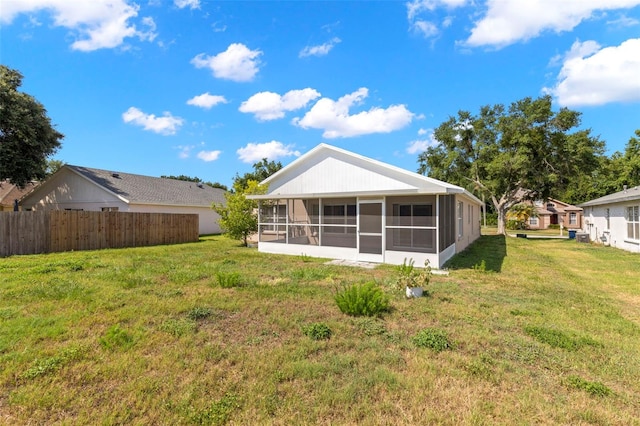 back of property with a lawn and a sunroom