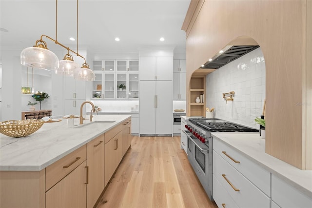 kitchen with sink, hanging light fixtures, double oven range, white cabinets, and wall chimney range hood