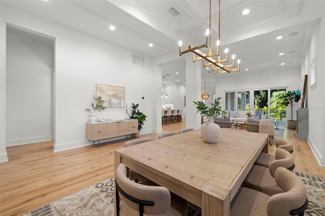 dining space with beam ceiling, light hardwood / wood-style floors, and a notable chandelier