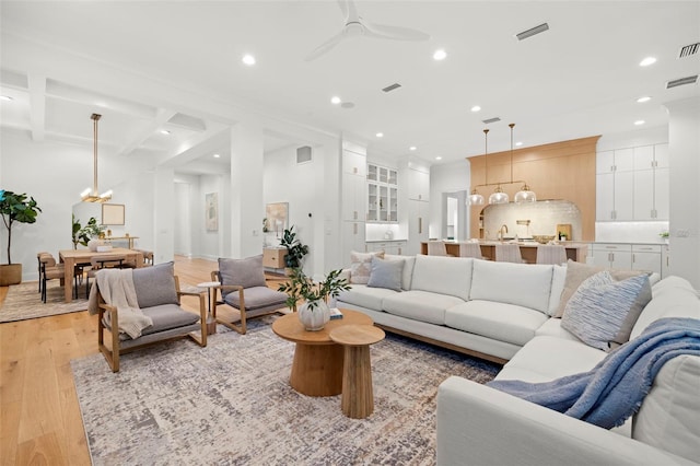 living room with coffered ceiling, ceiling fan, beam ceiling, and light wood-type flooring