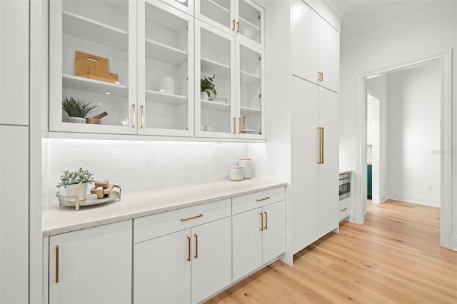 bar featuring white cabinetry, crown molding, tasteful backsplash, and light wood-type flooring