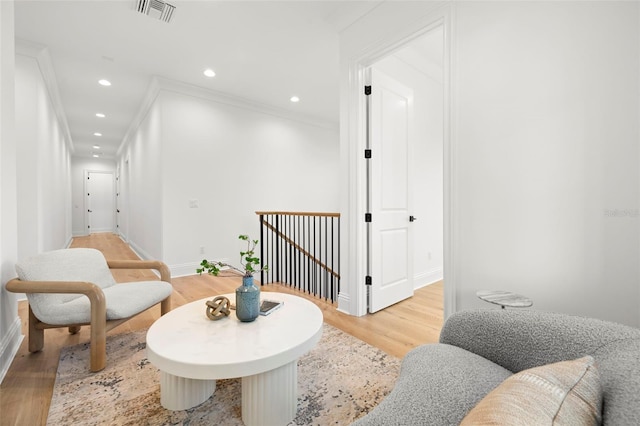 living area featuring crown molding and light hardwood / wood-style flooring