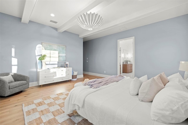 bedroom with hardwood / wood-style floors, beam ceiling, and ensuite bath