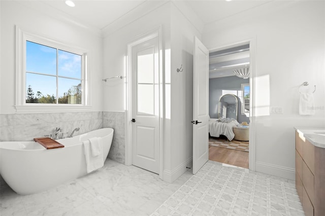 bathroom with crown molding, vanity, and a washtub