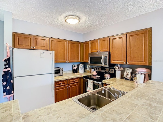 kitchen with tile countertops, sink, a textured ceiling, and appliances with stainless steel finishes