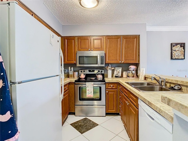 kitchen with crown molding, sink, a textured ceiling, light tile patterned flooring, and stainless steel appliances