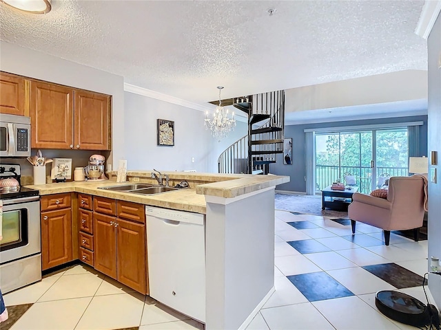 kitchen featuring pendant lighting, sink, a textured ceiling, kitchen peninsula, and stainless steel appliances