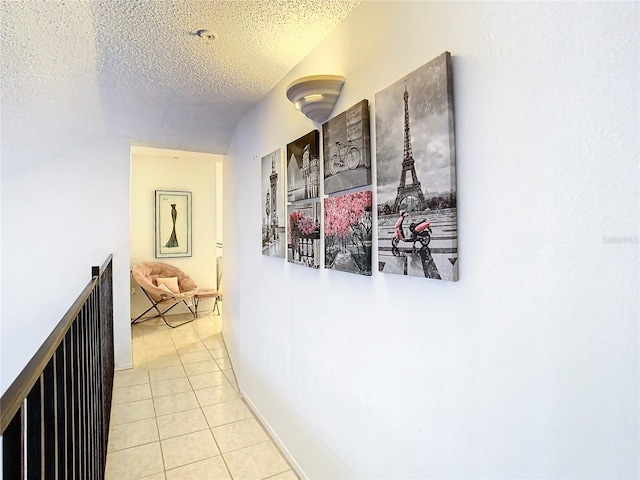 hallway featuring lofted ceiling, light tile patterned floors, and a textured ceiling