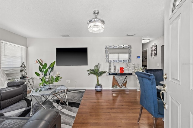 living room with dark hardwood / wood-style flooring, a textured ceiling, and an inviting chandelier