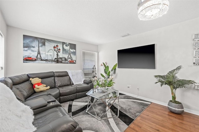 living room featuring hardwood / wood-style floors, a notable chandelier, and a textured ceiling