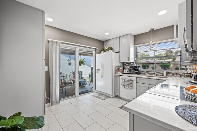 kitchen with white appliances, backsplash, sink, hanging light fixtures, and gray cabinets