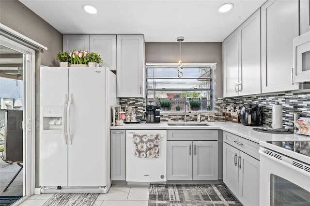 kitchen featuring decorative light fixtures, a healthy amount of sunlight, white appliances, and sink