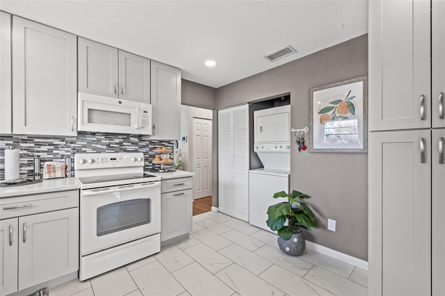 kitchen featuring tasteful backsplash, stacked washing maching and dryer, and white appliances