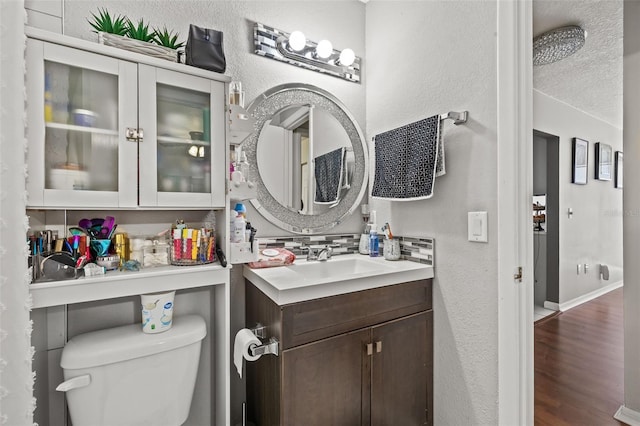 bathroom with a textured ceiling, vanity, hardwood / wood-style flooring, and toilet