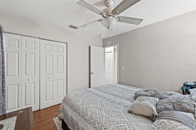 bedroom with ceiling fan, a closet, dark wood-type flooring, and a textured ceiling