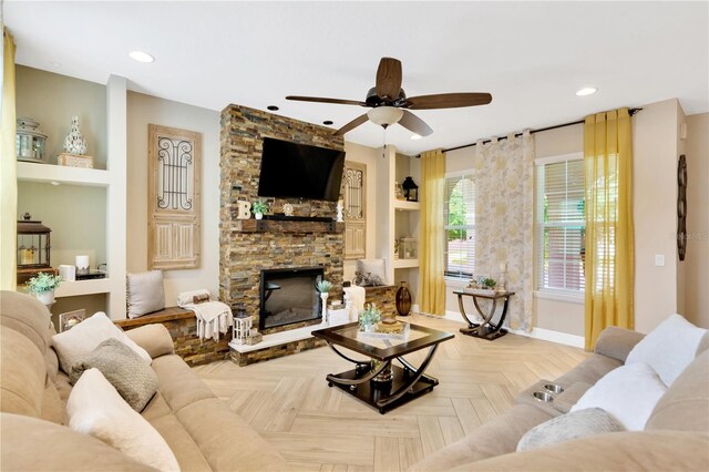 living room featuring built in features, ceiling fan, a fireplace, and light parquet flooring