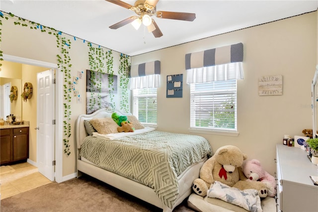 bedroom featuring light colored carpet, ensuite bathroom, and ceiling fan