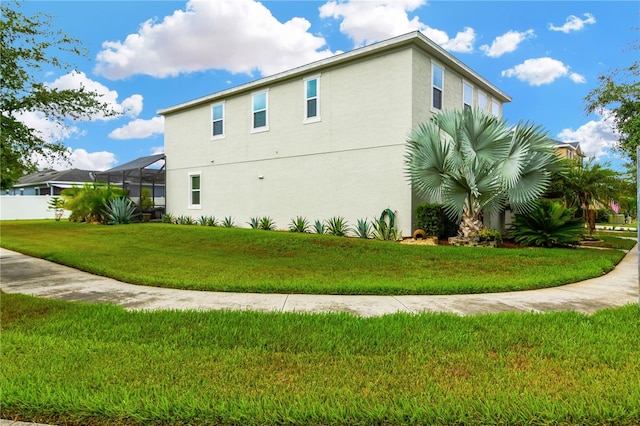 view of side of home with glass enclosure and a lawn