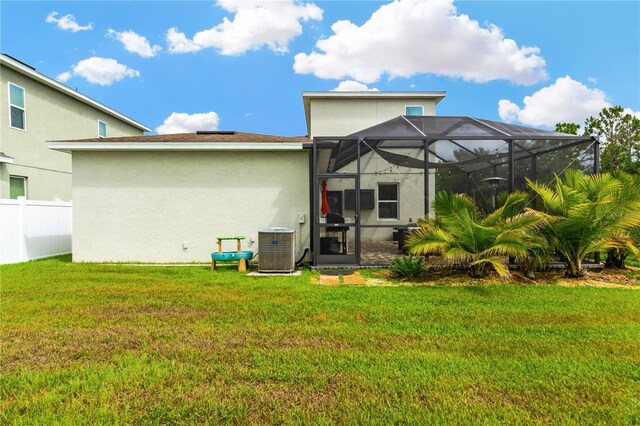 back of property featuring a yard, glass enclosure, and central air condition unit