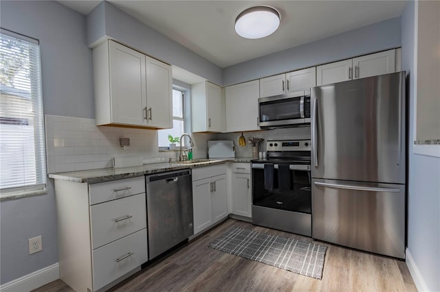 kitchen with decorative backsplash, sink, white cabinets, and stainless steel appliances