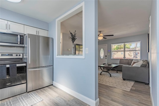 kitchen with decorative backsplash, appliances with stainless steel finishes, ceiling fan, light hardwood / wood-style floors, and white cabinetry