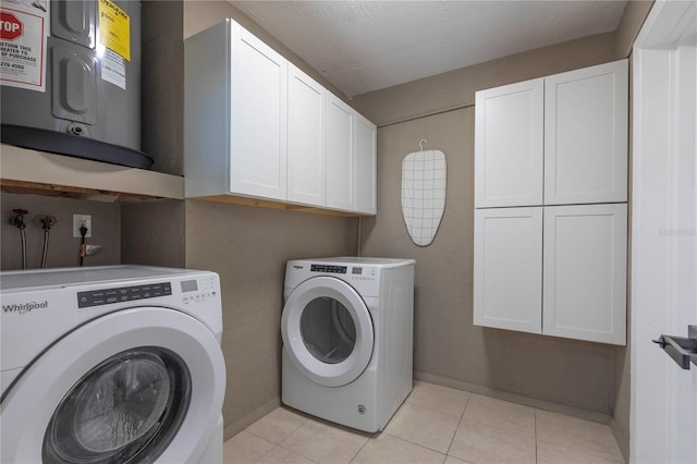 washroom featuring cabinets, a textured ceiling, water heater, light tile patterned flooring, and washing machine and clothes dryer