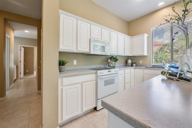 kitchen with white cabinetry, light tile patterned floors, and white appliances