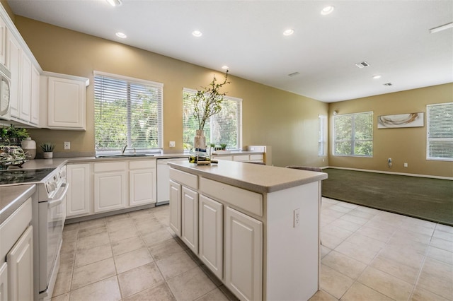 kitchen with white appliances, a kitchen island, sink, light tile patterned floors, and white cabinetry