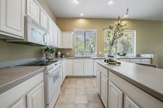 kitchen with plenty of natural light, sink, white cabinets, and white appliances