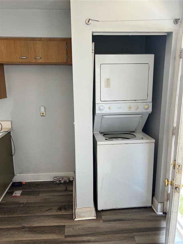 laundry room with stacked washing maching and dryer and dark wood-type flooring