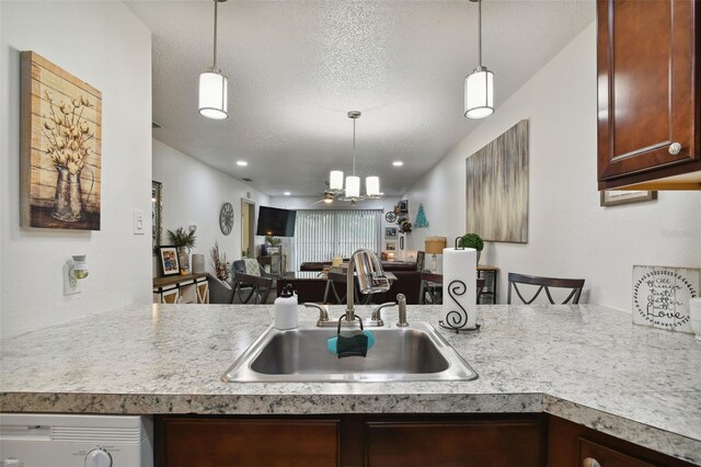 kitchen featuring dishwashing machine, pendant lighting, a textured ceiling, and sink