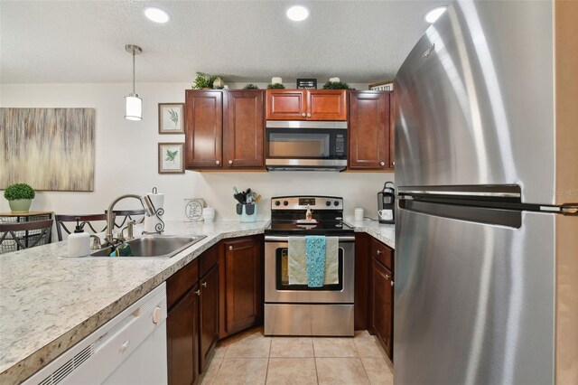 kitchen featuring a textured ceiling, stainless steel appliances, sink, hanging light fixtures, and light tile patterned flooring