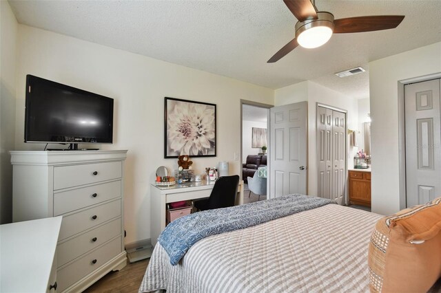 bedroom featuring dark hardwood / wood-style floors, ceiling fan, and multiple closets