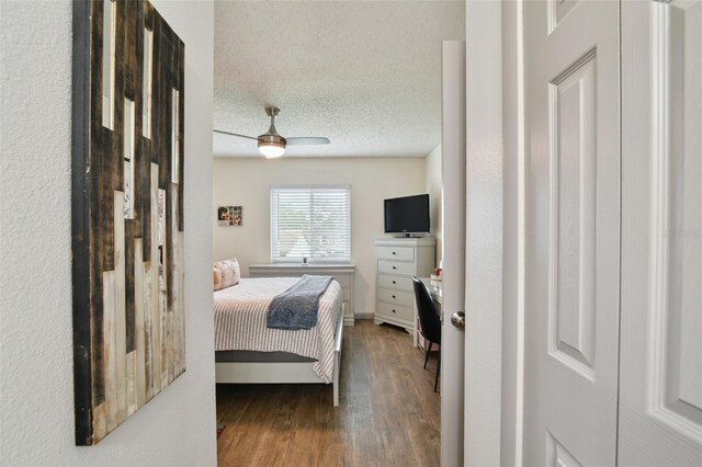 bedroom with a textured ceiling, hardwood / wood-style flooring, and ceiling fan