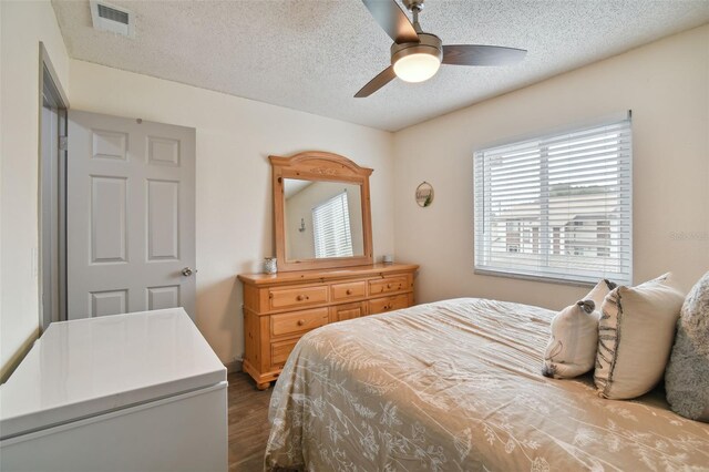 bedroom featuring hardwood / wood-style flooring, ceiling fan, and a textured ceiling