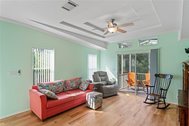 living room featuring a raised ceiling, light hardwood / wood-style flooring, ceiling fan, and a healthy amount of sunlight