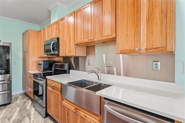 kitchen with appliances with stainless steel finishes, ornamental molding, and sink