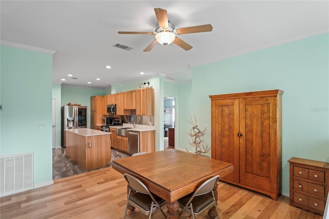 dining room featuring light hardwood / wood-style flooring, ceiling fan, ornamental molding, and sink