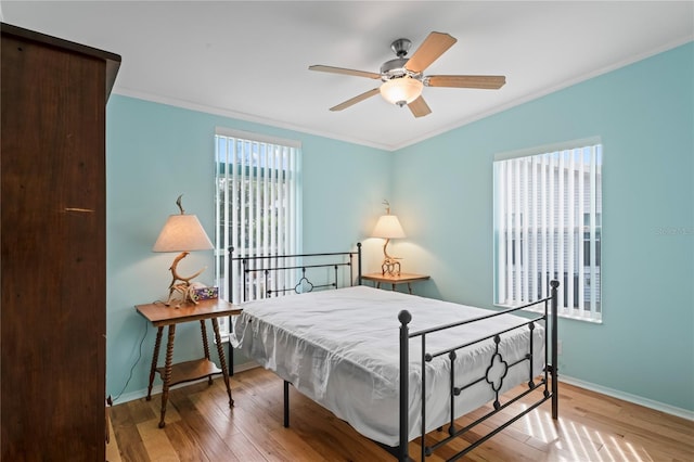 bedroom featuring hardwood / wood-style floors, ceiling fan, and crown molding