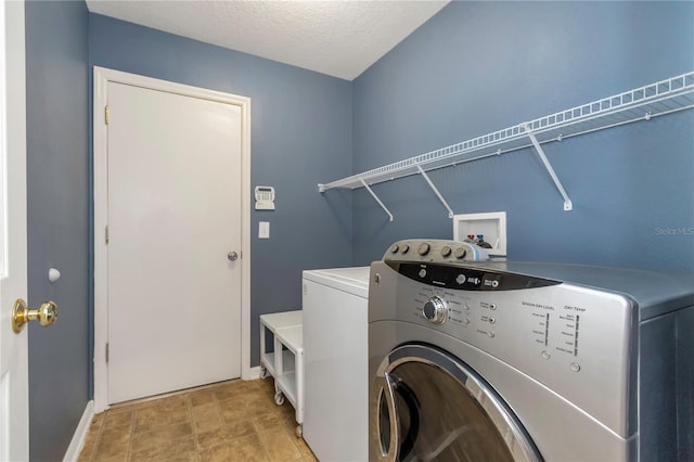 laundry area with separate washer and dryer and a textured ceiling