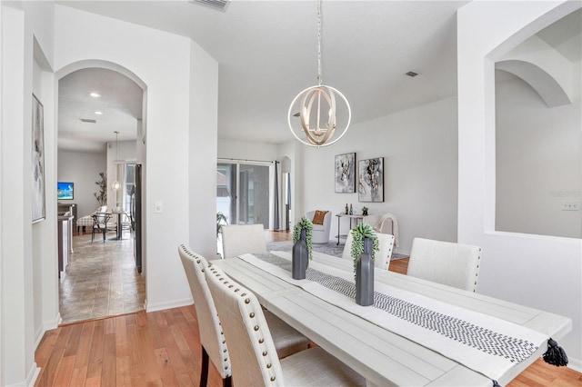 dining area with light wood-type flooring and an inviting chandelier